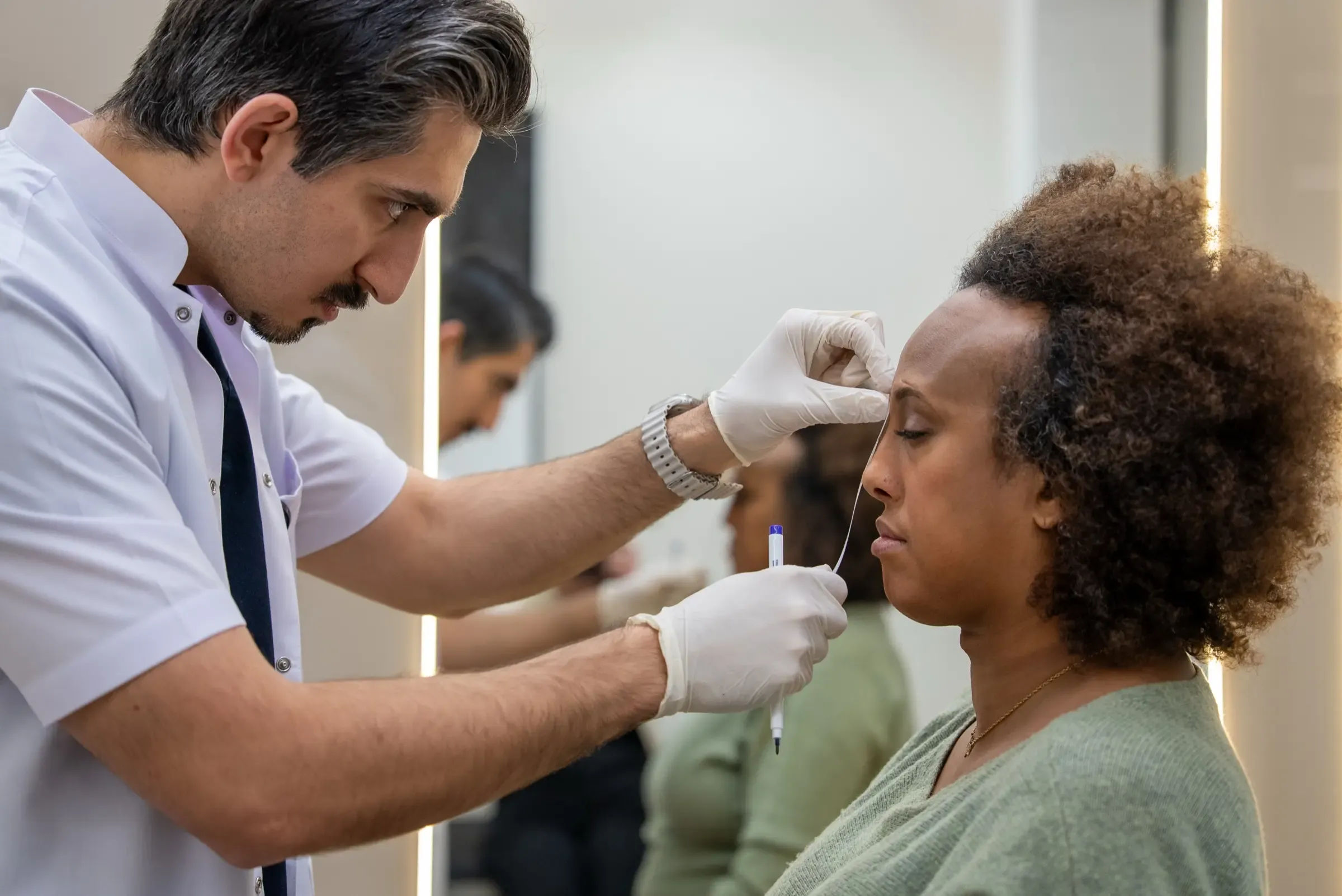 A Vera Clinic doctor marking the hairline of a patient with afro-textured hair during a consultation