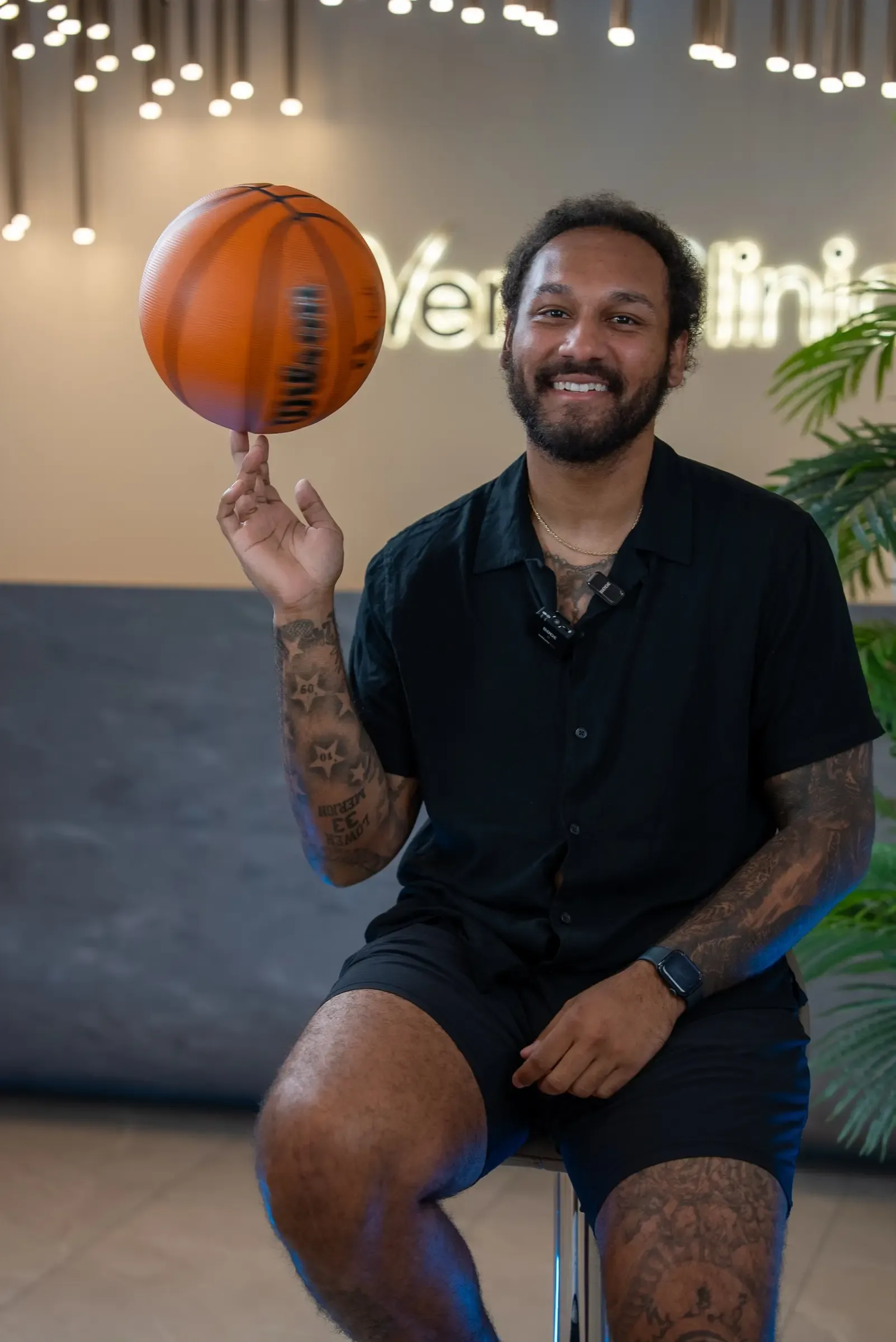 A smiling patient spinning a basketball on one finger in front of the Vera Clinic sign